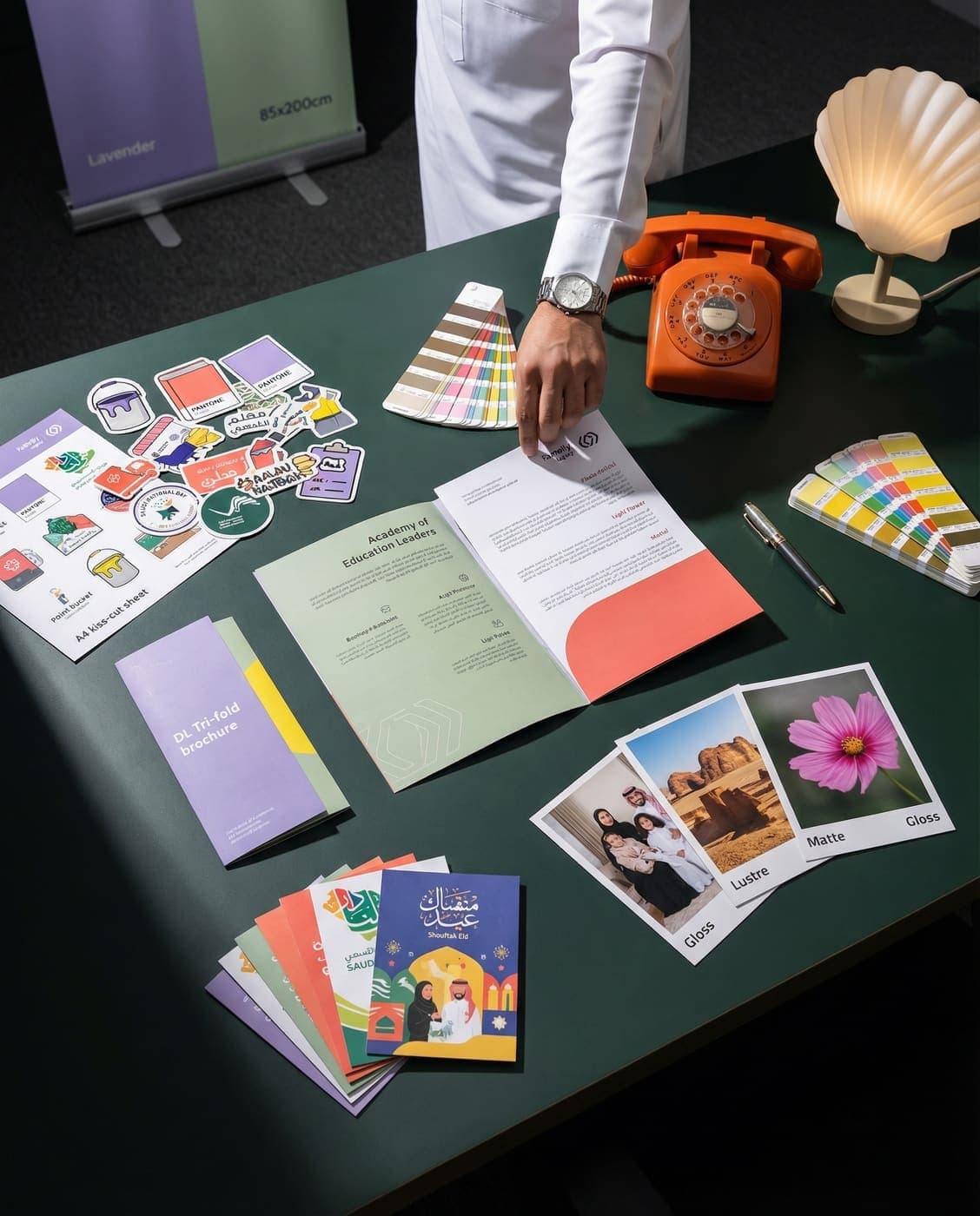 Premium print products — brochures, stickers, photo prints and roll-up banners on a green studio desk